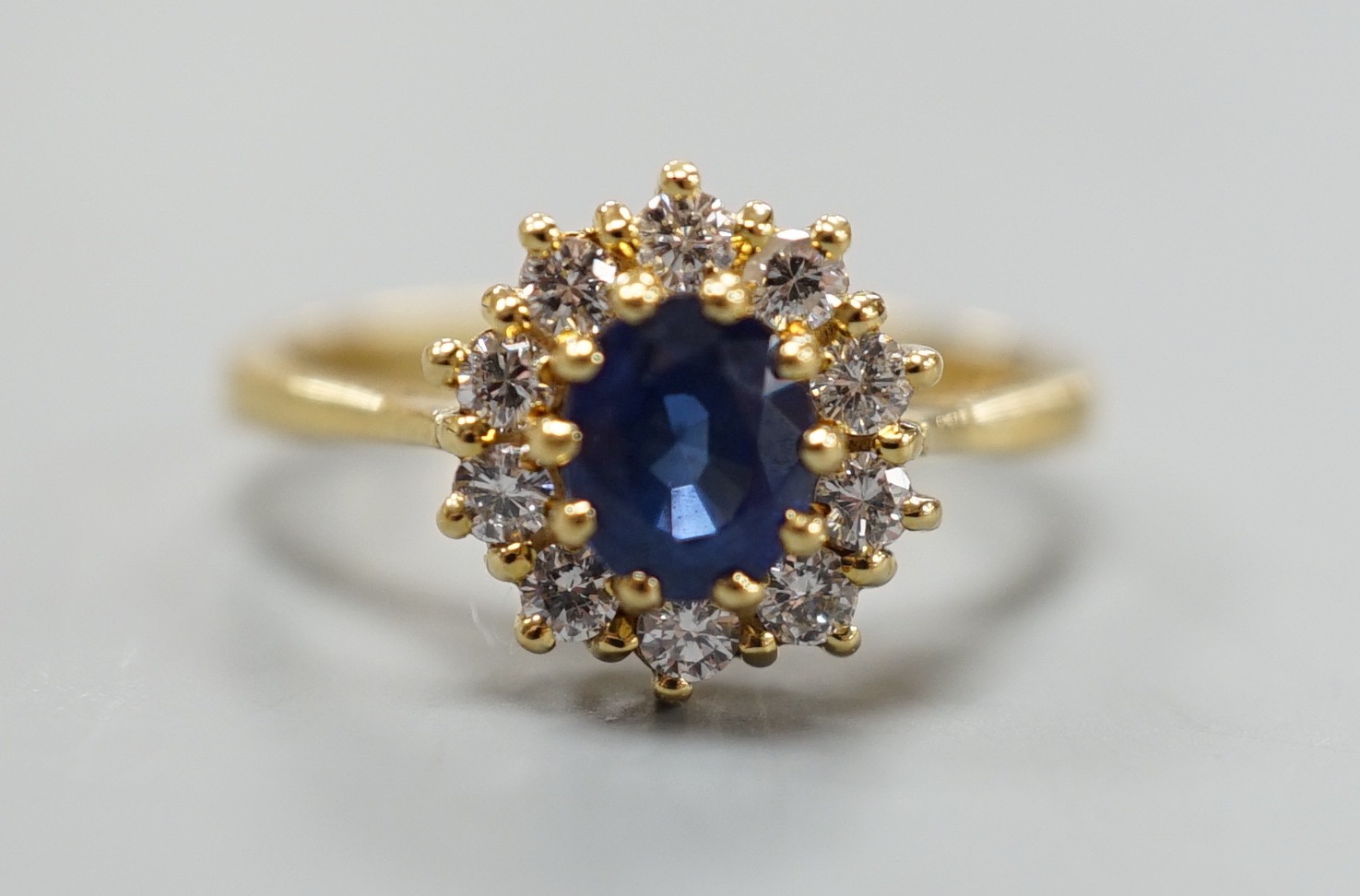 A modern 18ct gold, sapphire and diamond set oval cluster ring, size L, gross weight 3.8 grams